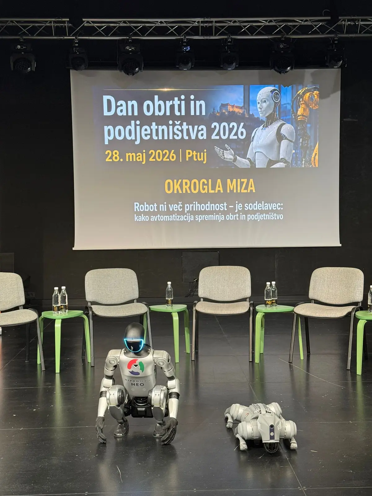 The HiProject NEO humanoid robot and a quadruped robot in front of the round-table slide.
