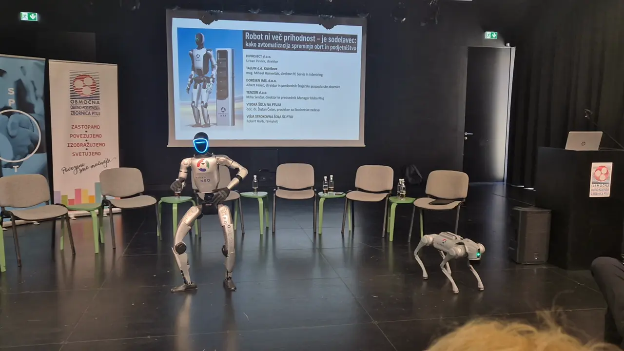 Humanoid and quadruped robot on stage in front of the round-table slide.